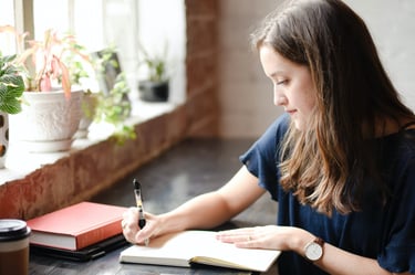 Young woman writing at a desk, symbolizing personalized guidance in crafting compelling SoPs and LOR