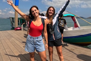 two women standing on a wooden deck with a boat in the background, Snorkeling & Keliling Pulau Gili 
