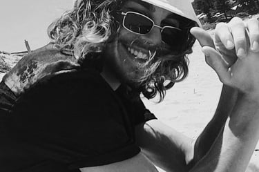 a man in a hat and sunglasses on a beach