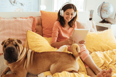a woman sitting on a bed with a dog and a laptop