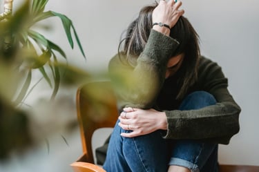 Unrecognizable upset lady embracing knees sitting on chair