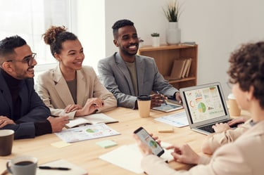 Diverse business team collaborating in a bright office meeting while analyzing data on a laptop.