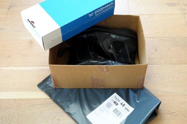 a box of shoes is sitting on a box with returns envelope and foot impression box
