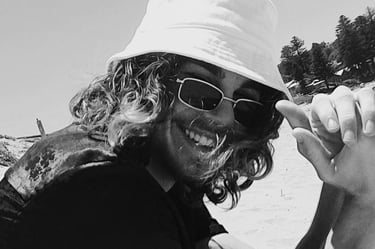 a man in a hat and sunglasses on a beach