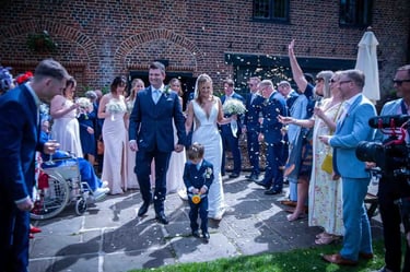 A happy bride and groom walking through a confetti toss at their outdoor wedding ceremony.