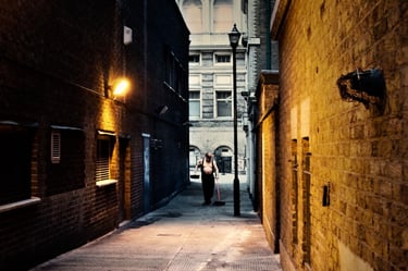 An early morning photograph of an elderly man without a shirt cleaning an alleyway in central London, captured early morning
