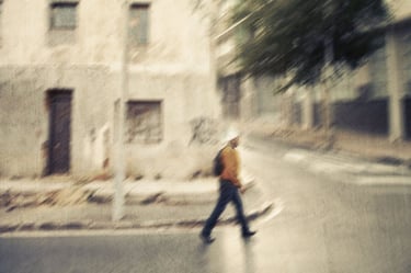 Early morning street scene in Woodstock, Cape Town, with soft sunlight illuminating a single pedestrian crossing the road