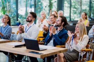 a group of people sitting at a table with laptops