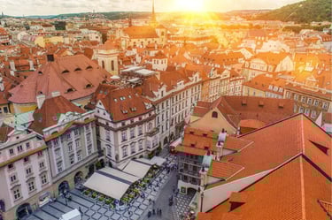 Sunset over Prague Old Town Square featuring historic red rooftops and European architecture.