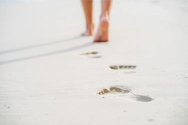 pieds nus laissant des empreintes sur le sable symbolisant le cheminement personnel en sophrologie