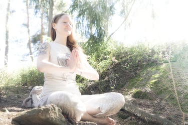 a woman meditating on a rock in a forest