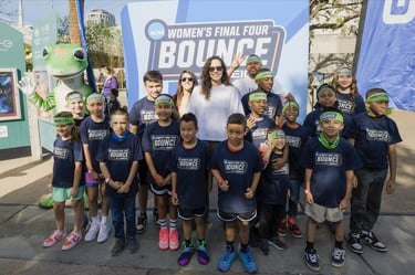 Children in matching blue shirts at the NCAA Women's Final Four Bounce event with GEICO gecko mascot.