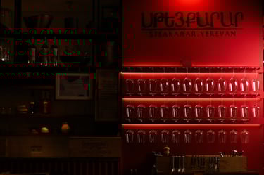 Steakarar interior in Yerevan featuring backlit red shelves with hanging crystal wine glasses.