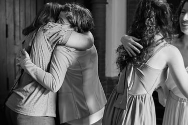 Brides hugging wedding guests after ceremony.