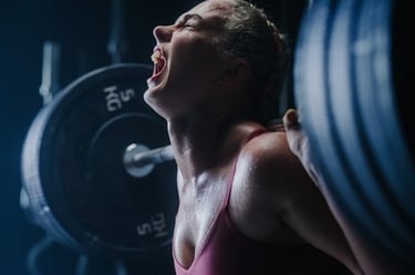 Athletic woman shouting with effort while performing a heavy barbell back squat in a gym.