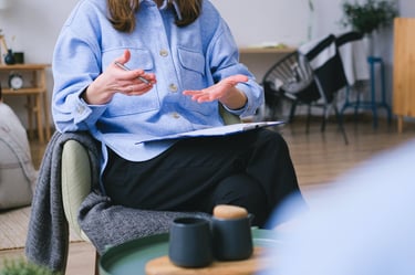 a woman in a blue shirt and black pants sitting in a chair