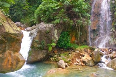 Air terjun Curug Ciburial yang sejuk mengalir di antara pepohonan rimbun ke kolam alami yang tenang, menampilkan suasana asri