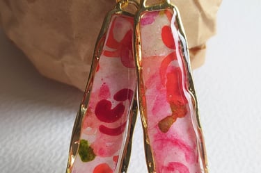 a pair of earrings with a pink flower