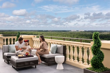 Family relaxing on the private terrace of the Royal Suite at Four Seasons Orlando with a view of Walt Disney World.