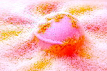 XL pink and coral bath bomb dissolving with dense foam and vibrant color bloom.