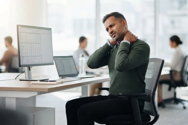 Office worker experiencing neck and shoulder discomfort after extended computer use.