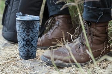 a person standing in the grass with a cup of coffee
