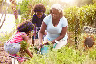 Una mujer afro con dos crios en un jardin