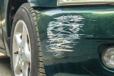 Auto verde con rayón en el parachoque causado por roce entre autos