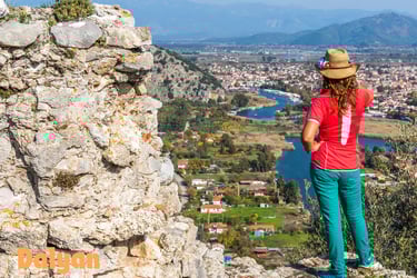 a woman standing on a rock formation with a view of a city