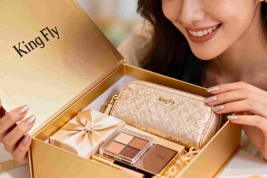 A woman smiling as she unboxes a luxury GWP gift set containing a gold cosmetic pouch.