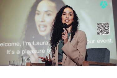 a woman in a suit and a microphone in front of a screen while ohaio livespeaker works