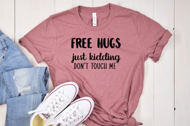A pink t-shirt, jeans and sneakers. The t-shirt reads "Free Hugs - just kidding - don't touch me"