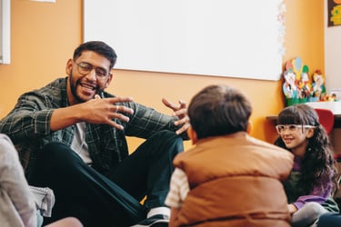 A teacher sitting on the floor with a small group of students in a classroom.