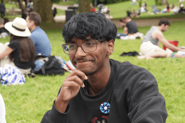a man in a black shirt and glasses sitting on a blanket qui est adhérent de néoléa