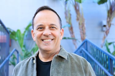a man in a jacket and jeans standing in front of stairs