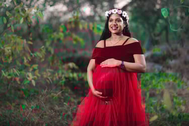 "Pregnant woman in a flowing gown holding her baby bump, radiating joy and love in a serene outdoor 