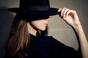 trait fin d’une femme posant de profil avec chapeau, ombre sous les yeux, éclairage au flash