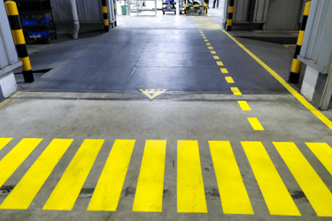Suelo de una fabrica con paso de peatones con las líneas pintadas de amarillo.