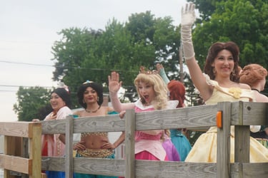Princesses riding in a parade and waving