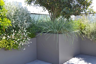 terrasse ou balcon aménagé avec des bacs contenant des arbustes, graminées et plantes fleuries