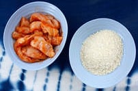 raw chicken fingers marinating in sriracha sauce and panko bread crumbs