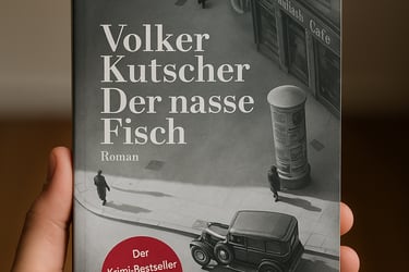 Hand hält den Roman ‚Der nasse Fisch‘ von Volker Kutscher vor einem neutralen Hintergrund.