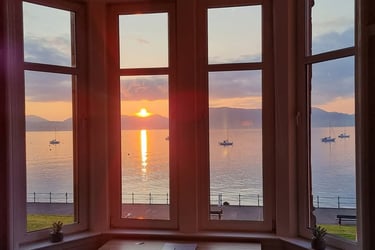 The window at Gourock Seaview Holiday Let with a view of the sun setting over the water