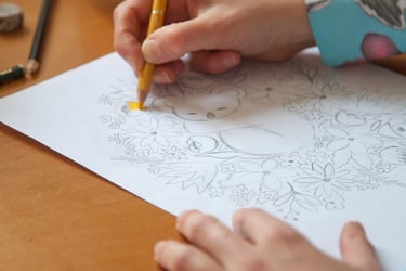 Hands making a koala illustration with colored pencils