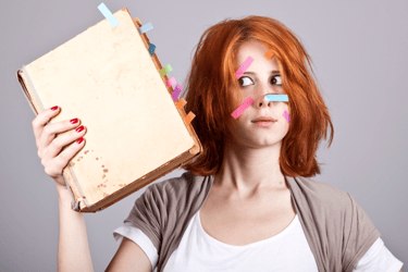 Photo of a woman holding a manuscript. Both the book and her face have colored sticky tabs on them