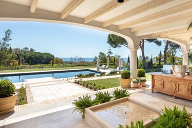 View from the shaded porch across the pool, with the Mediterranean Sea visible in the background.