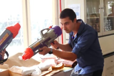 a man and woman are playing with a toy gun