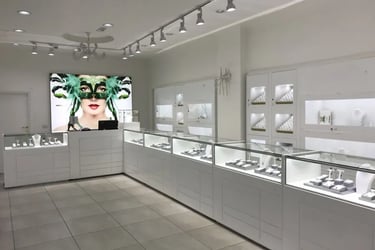 Modern white jewelry store interior with luxury glass display cases and bright track lighting.
