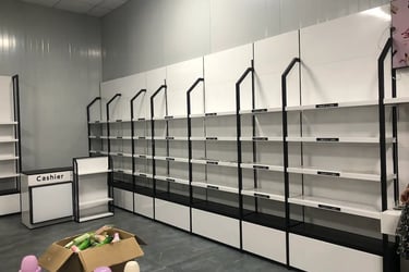 Empty white and black cosmetic display shelves and cashier counter in a retail skin care store.