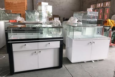 Modern white and black retail glass display cases with locking storage cabinets in a warehouse.